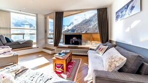 Een moderne woonkamer met een groot raam, een flatscreen televisie en een gezellige zithoek.