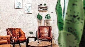 Ein gemütliches Wohnzimmer mit einem runden Couchtisch, zwei Ledersesseln und einer großen Topfpflanze.