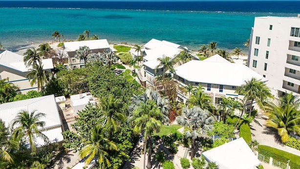 A resort with white buildings, palm trees, and a view of the ocean. - Ocean view 1BR, 1 min to beach, shared pool (Rum Point)