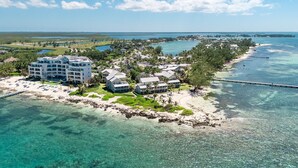 A coastal resort with multiple buildings, a beach, and clear blue waters. - Ocean view 1BR, 1 min to beach, shared pool (Rum Point)