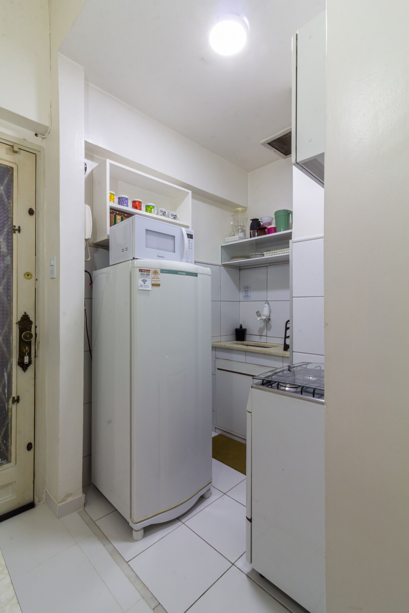 Una cocina compacta equipada con refrigerador, microondas y estufa a gas.