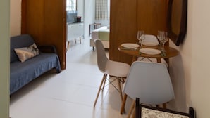 A room with a wooden sliding door, a dining table with chairs, a sofa, and a ceiling fan. - Comfort in Copacabana - STC405 (Rio de Janeiro)