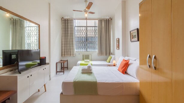 A hotel room with a bed, a TV, a desk, a wardrobe, and a window with curtains. - Comfort in Copacabana - STC405 (Rio de Janeiro)