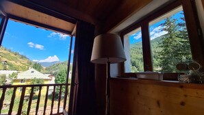 Eine Holzhütte mit einem Balkon mit Blick auf eine gebirgige Landschaft.