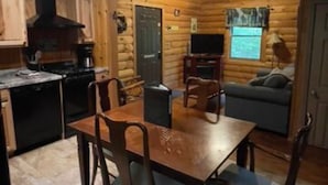 Un intérieur chaleureux de chalet en bois, comprenant un coin repas, une cuisine et un espace de vie.