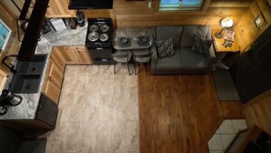 A compact kitchen with a stove, sink, and dining area. - The Maple Tree Cabin (Bruceton Mills)