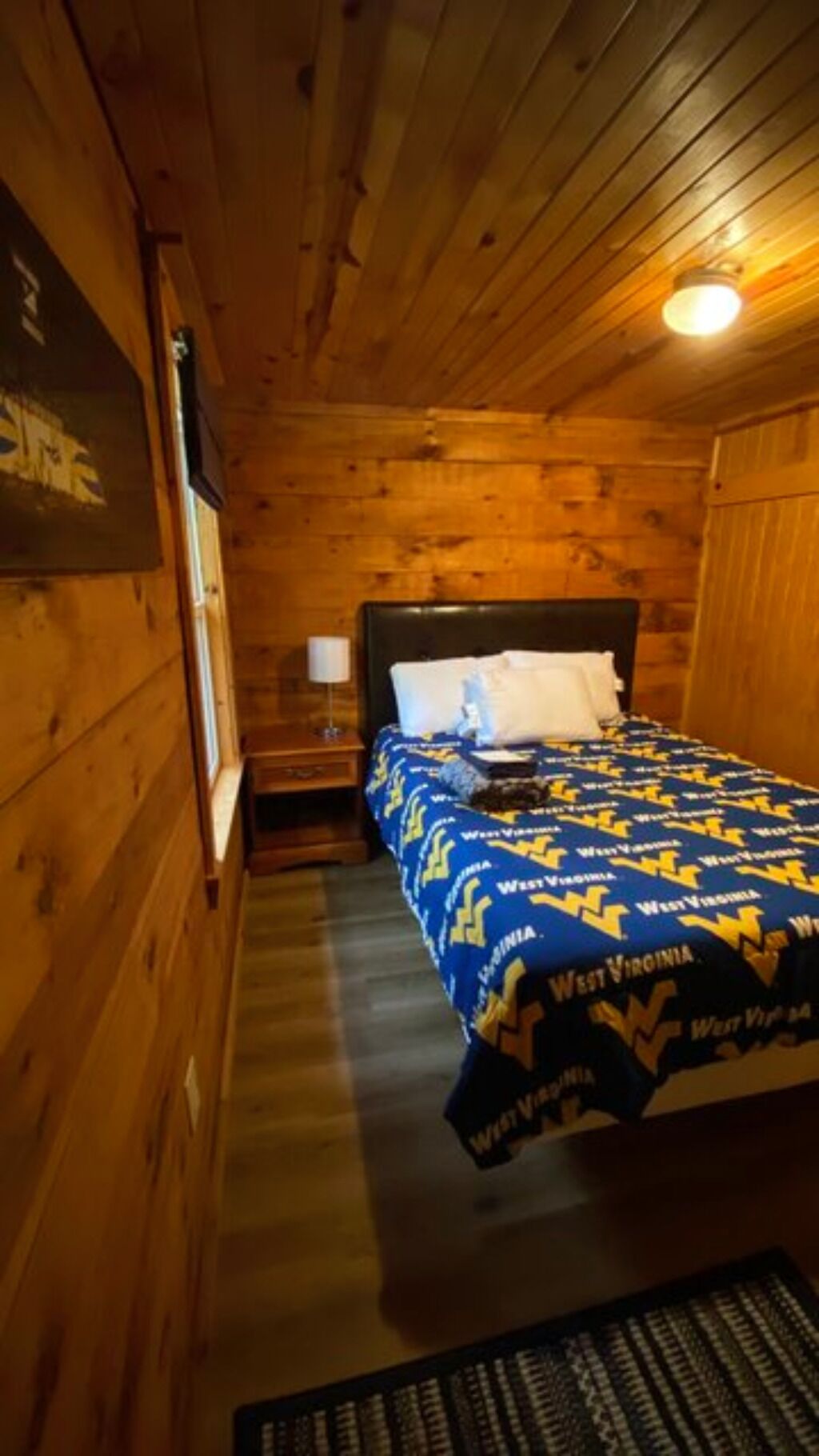 Una camera arredata in stile baita con un letto, un comodino e una lampada a muro.