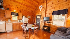 L’intérieur d’une cabane en bois comprend un coin repas, une cuisine et un espace de vie.