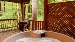 A hot tub on a wooden deck with a view of a forest. - The Shawnee Cabin w/ Queen Bed (Bruceton Mills)