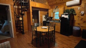 A compact kitchen with wooden cabinets, a dining table with chairs, a built-in stove, and a small refrigerator. - The Shawnee Cabin w/ Queen Bed (Bruceton Mills)
