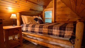 A cozy wooden cabin room with a bed, a nightstand, and a window. - The Shawnee Cabin w/ Queen Bed (Bruceton Mills)
