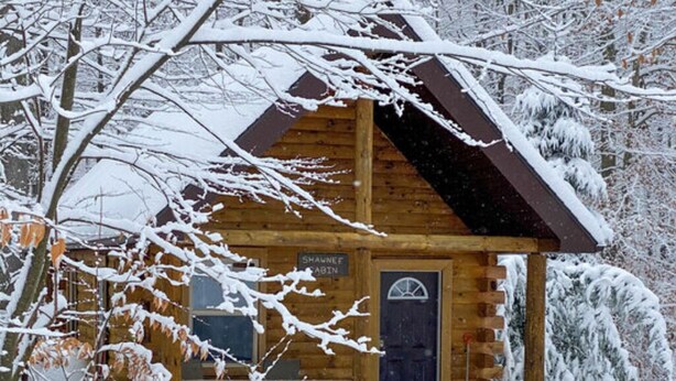 A log cabin with a dark door and a sign reading "Shawnee Cabin." - The Shawnee Cabin w/ Queen Bed (Bruceton Mills)