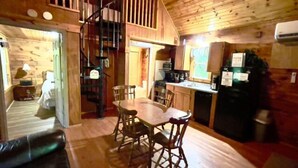 Un intérieur de chalet chaleureux comprenant un coin repas, une cuisine et un escalier en colimaçon.