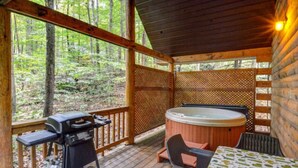 Une terrasse en bois avec un jacuzzi, un barbecue et une table entourée de chaises.