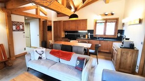 Una sala de estar acogedora con un sofá, una mesa de comedor y una cocina con armarios de madera y una ventana.