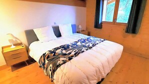 Un dormitorio con cama, mesita de noche, lámpara y ventana con cortinas.