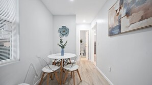Un comedor moderno con una mesa redonda y sillas, un jarrón con una planta y un cuadro abstracto grande en la pared.
