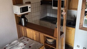 A compact kitchen with a microwave, coffee maker, and a wooden countertop. - Charming 2-room Apartment for 4/6 People (Bessans)