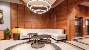 A modern lobby with a curved wooden wall, a white sofa, and a circular chandelier. - 2BR Elegant French Quarter Escape The Mayfair (New Orleans)