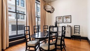 A dining area with a round table and chairs, a pendant light, and framed artwork on the wall. - 2BR Elegant French Quarter Escape The Mayfair (New Orleans)