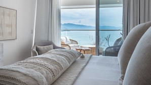 Et soveværelse med en stor seng, havudsigt og en balkon med udendørs siddepladser.