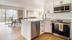 A modern kitchen with white cabinets, stainless steel appliances, and a large island. - City & Palm View Oceanfront Bliss w/ Free Parking (Honolulu)
