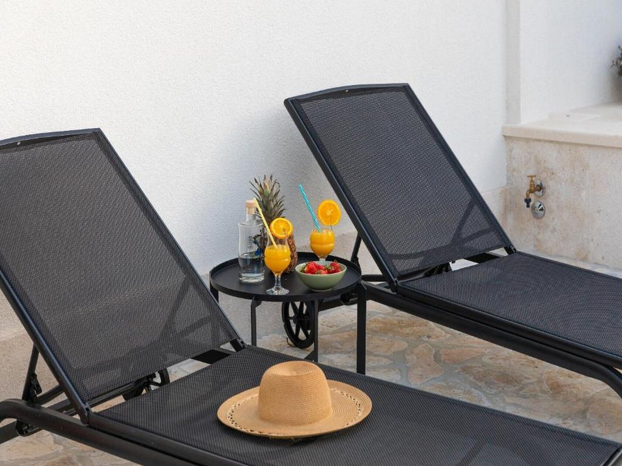 Deux fauteuils confortables, une petite table placée entre eux, un chapeau sur la table et une boisson avec une paille.