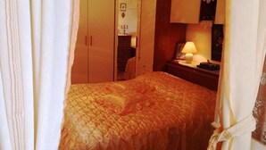 Un dormitorio con cama, armario, mesita de noche y lámpara.