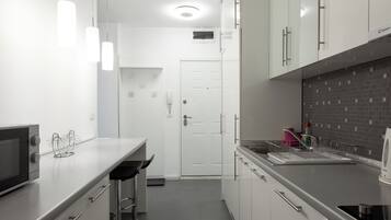 Una cocina moderna con gabinetes blancos, electrodomésticos de acero inoxidable e iluminación colgante.