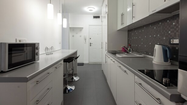 A modern kitchen with white cabinets, stainless steel appliances, and pendant lighting. - Central Studio Apartments (Belgrade)