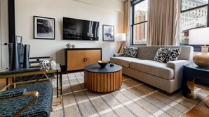 A modern living room with a sofa, a coffee table, a TV, and artwork on the wall. - 2BR Cityscape 2 Blocks from Bourbon St The Mayfair (New Orleans)