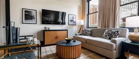 A modern living room with a sofa, a coffee table, a TV, and artwork on the wall.
