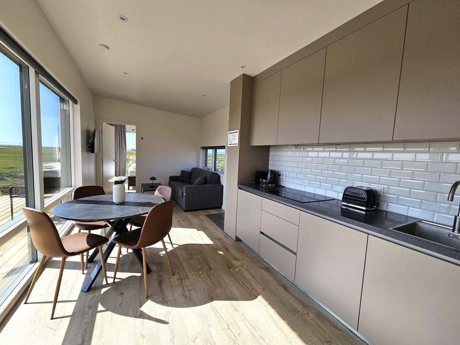 Una cocina moderna con un amplio ventanal, una zona de comedor con mesa y sillas, y vistas al exterior.