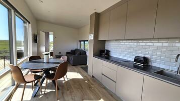 Una cocina moderna con un amplio ventanal, una zona de comedor con mesa y sillas, y vistas al exterior.