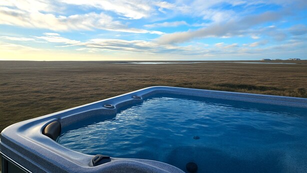 A hot tub with a view of a flat landscape and a partly cloudy sky. - Hítarneskot – Private Hot Tub Cottage in Snæfellsnes (Borgarnes)
