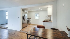 Eine moderne Küche mit Edelstahlgeräten, ein Essbereich mit Holztisch und Blick auf den angrenzenden Wohnbereich.