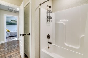 A bathroom with a white bathtub, a towel rack, and a showerhead. - Rider’s Retreat! Modern Home By Bella Vista Trails (Bella Vista)