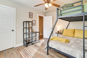 A bunk bed with a green mattress, a wooden ceiling fan, and a small table with a lamp. - Rider’s Retreat! Modern Home By Bella Vista Trails (Bella Vista)