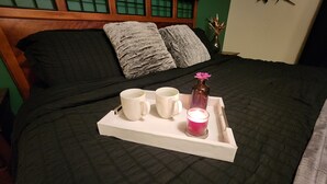 A bed with a tray holding two white mugs, a candle, and a decorative vase. - The Oasis: Private 85° Pool + Bonus Shared Spa & Resort Garden
 (Kennewick)