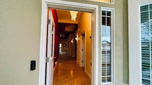 A hallway with a door leading to a room, a window with blinds, and a doorbell on the wall. - The Oasis: Private 85° Pool + Bonus Shared Spa & Resort Garden
 (Kennewick)