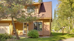 A two-story house with a garage, a covered porch, and a small front yard with a tree and shrub. - Riverside Serenity - Rivershire Retreat Guesthouse (Traverse City)