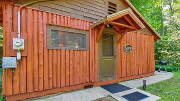 Une petite cabane en bois avec une porte, une fenêtre et une enseigne sur laquelle on peut lire : « The Cabin Riverside ».