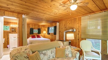 L’intérieur d’un chalet en bois, avec un lit, un canapé, un fauteuil et un ventilateur de plafond.
