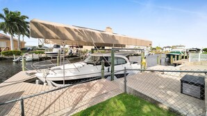 En småbåtshamn med förtöjda båtar, en överbyggd ramp för att sjösätta båtar och ett inhägnat område med en gräsyta framför.