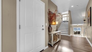 A spacious entryway with a white door, a console table with a vase, and a staircase leading to an upper level. - Lakefront Home w/ Mountain Views • Walk to Shops (Sparks)