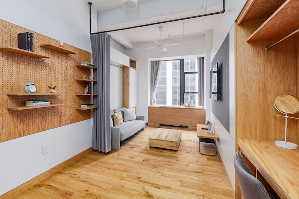 Unwind in a sunlit studio lounge with warm wood floors.