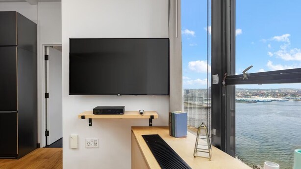 Une chambre moderne dotée d’une grande fenêtre, d’un téléviseur à écran plat fixé au mur, d’un bureau en bois et offrant une vue sur une étendue d’eau.