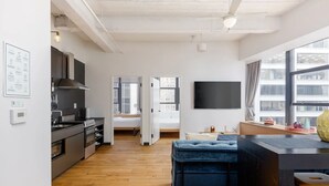 Eine moderne Küche mit einer großen Kochinsel, einem Essbereich mit einem blauen Sofa und einem an der Wand befestigten Fernseher.