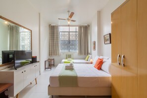 A hotel room with a bed, a TV, a desk, a wardrobe, and a window with curtains. - Comfort in Copacabana - Stc405 (Rio de Janeiro)