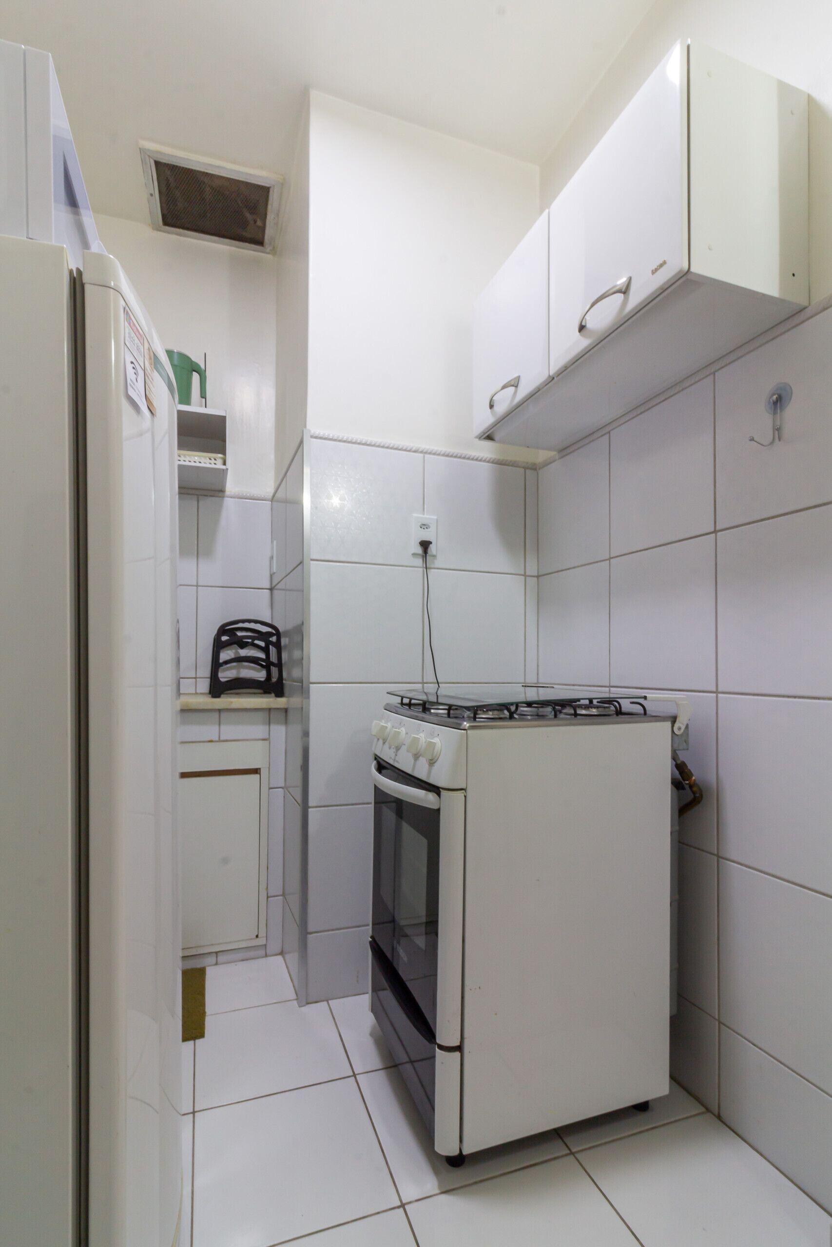 Una cocina funcional con armarios blancos, estufa y refrigerador.